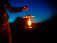 man holding the vintage lamp with a candle outside. Copy space for your text