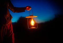 man holding the vintage lamp with a candle outside. Copy space for your text