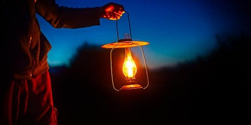 man holding the vintage lamp with a candle outside. Copy space for your text
